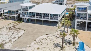 Una propiedad frente a la playa con varias edificaciones, incluyendo un amplio espacio cubierto con asientos y una piscina.