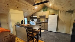 Une cuisine avec des poutres apparentes en bois au plafond, une table à manger avec des chaises, un réfrigérateur et un four à micro-ondes.