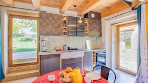 A modern kitchen with wooden beams, a dining area with a red tablecloth, and a view of the garden. - Un Temps Pour Soi - ANTULLY (ANTULLY)