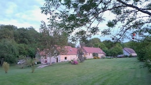 A stone building with a red roof, surrounded by a grassy field and trees. - Un Temps Pour Soi - ANTULLY (ANTULLY)
