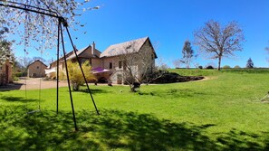 A stone house with a sloped roof, a swing set, and a grassy yard. - Un Temps Pour Soi - ANTULLY (ANTULLY)