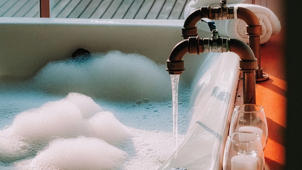 Ein Badezimmer mit Fenster, einem laufenden Wasserhahn und einem Glas Wasser.