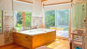 Ein modernes Badezimmer mit einer Holzwanne, großen Fenstern und einer Duschkabine.