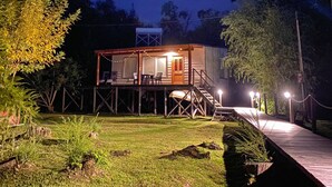 Ein zweistöckiges Haus mit einer Terrasse, Sitzgelegenheiten im Freien und einem Weg zum Eingang.