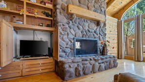 A stone fireplace with a TV, wooden shelves, and a wooden floor. - Wilderness- Sedona Villas (Sedona)