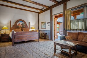 Una habitación con una cama y una mesa de madera, un sofá y una ventana con cortinas.