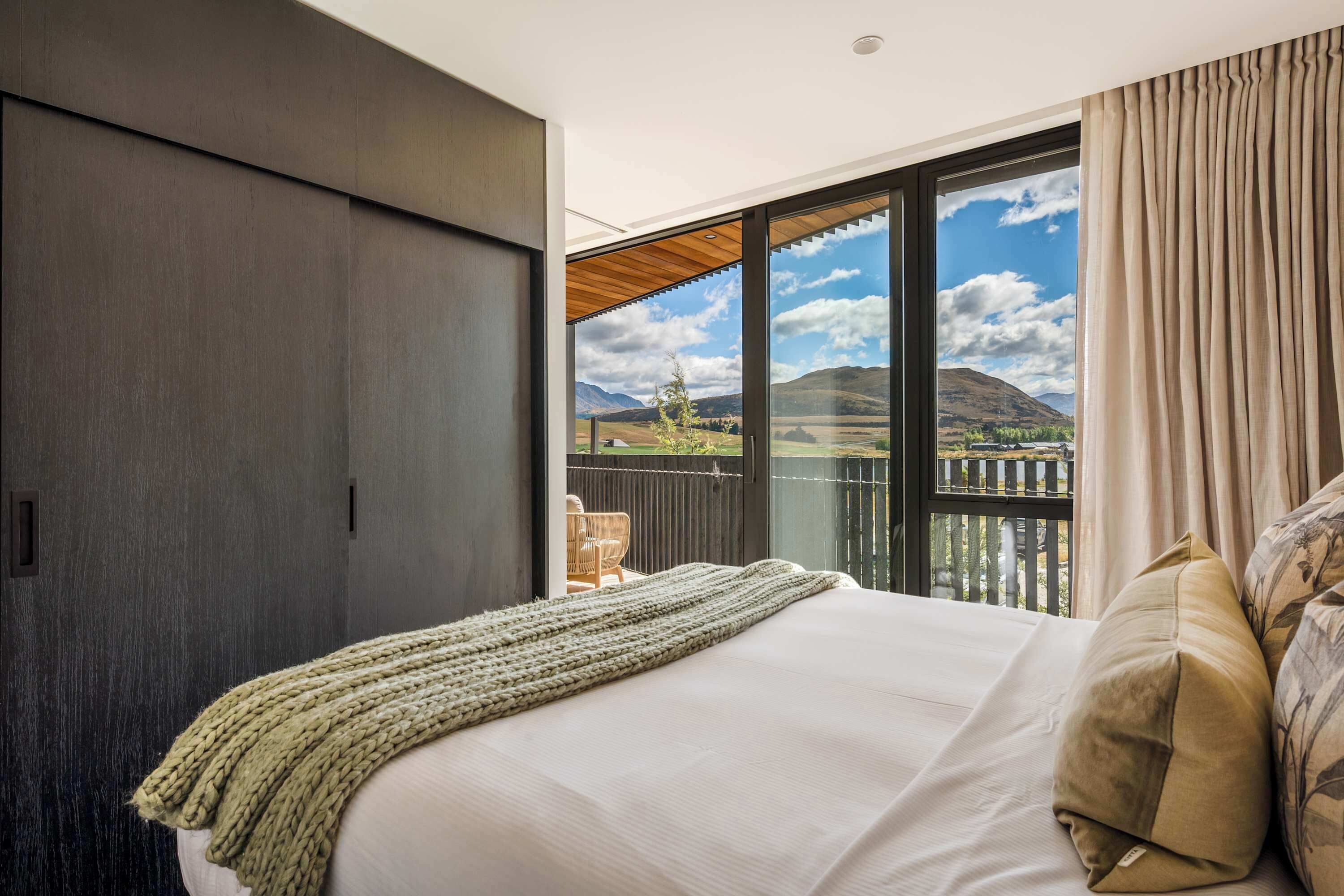 Une chambre avec un grand lit, une vue sur l’extérieur et une porte coulissante.