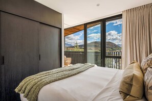 Ein Schlafzimmer mit einem großen Bett, Blick ins Freie und einer Schiebetür.