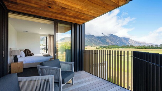 Un balcon avec un lit, une chaise et une vue sur les montagnes.
