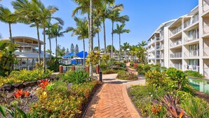 Ein Resort mit Pool, Palmen und einem Pflasterweg.