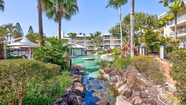 Ein Resort mit Swimmingpool, Palmen und einem mehrstöckigen Gebäude.