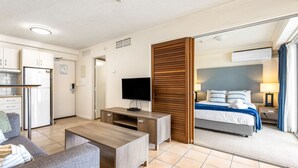 Ein Hotelzimmer mit Bett, Fernseher, Schreibtisch, Sofa und Spiegel.