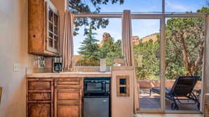A kitchen with wooden cabinets, a dishwasher, and a window overlooking a mountainous landscape. - Sunset- Sedona Villas (Sedona)