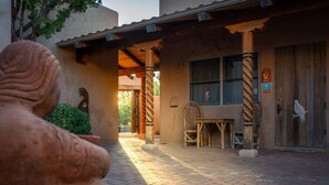 A rustic building with a covered patio, a wooden chair, a table, and a bird mural on the door. - Sunset- Sedona Villas (Sedona)