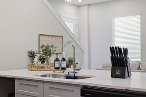 A kitchen with a modern faucet, a dish soap dispenser, and a knife block on the counter. - Unwind 15 Min from Dwntn Houston in Tranquility! (Houston)