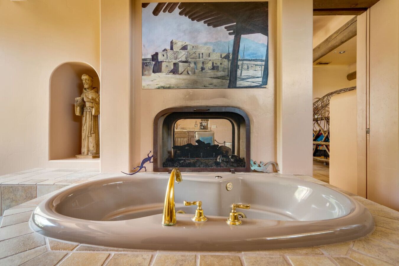 A bathroom with a large bathtub, a statue, and a painting above the bathtub.