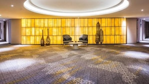 A spacious lobby with a central seating area, a patterned floor, and a wall with illuminated panels. - Aber Al Takhassusi Hotel (Riyadh)