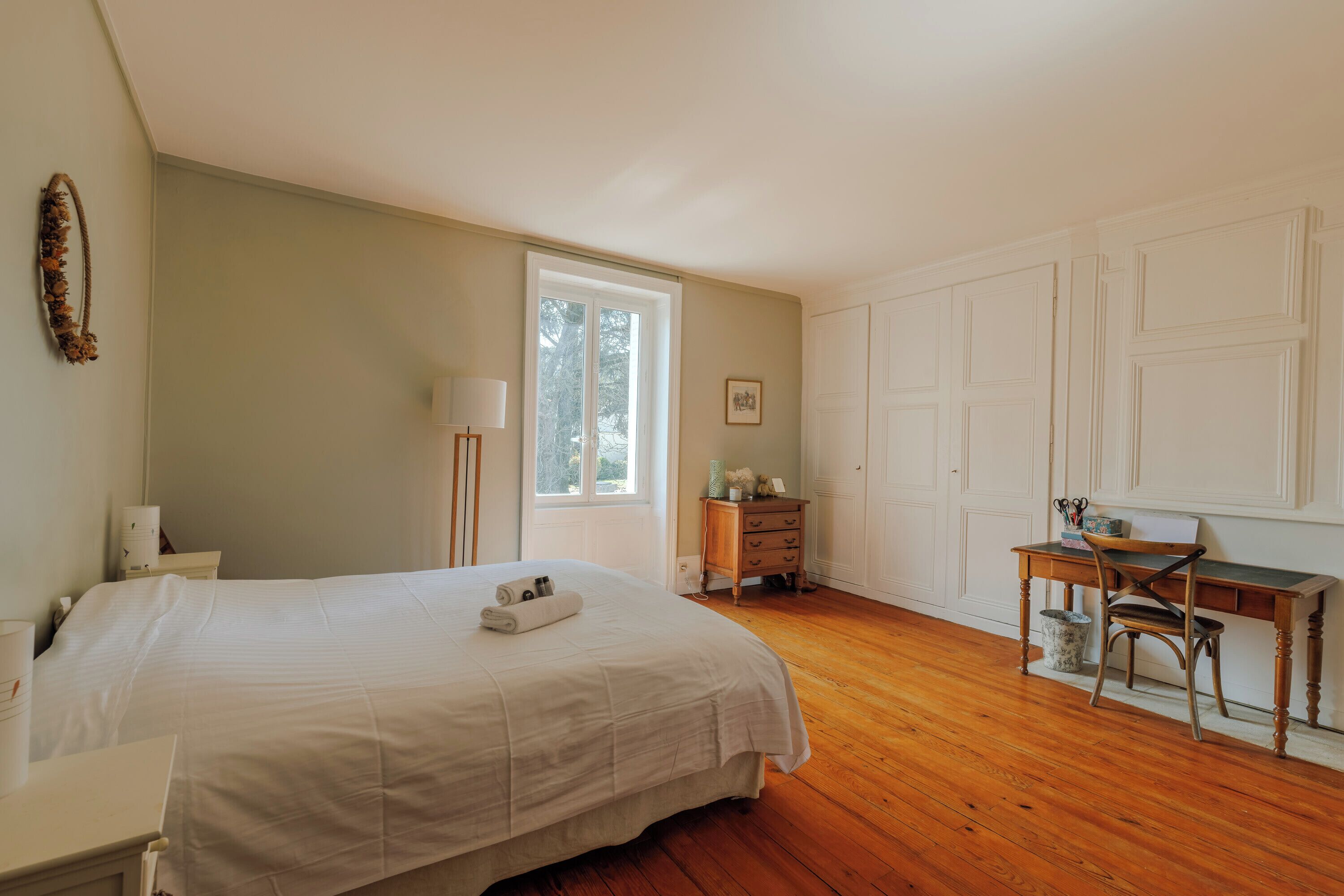 A bedroom with a bed, dresser, desk, chair, and a window.