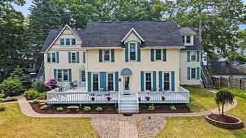 A two-story house with a front porch, a small garden, and a driveway.