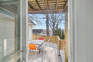 En terrasse med bord og stole, et træhegn og udsigt til et hus og træer.