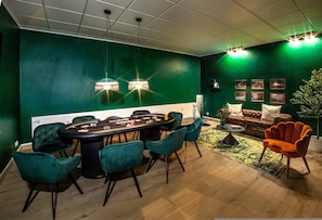 Una habitación con pared verde, una mesa redonda con sillas, un sofá y una lámpara.
