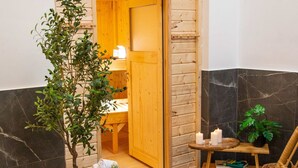A spa area with a wooden door, a small table with candles, a wicker chair, a hot tub, and a potted plant. - Casino 2 - Sauna Whirlpool Game-zone (Hoehr-Grenzhausen)
