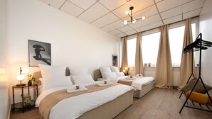 A hotel room with two beds, a bedside table with a lamp, a wall-mounted artwork, and a window with curtains. - Casino 2 - Sauna Whirlpool Game-zone (Hoehr-Grenzhausen)