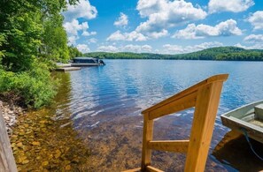 Eine Holzsteganlage, die sich in einen stillen See erstreckt, mit einem Boot am gegenüberliegenden Ufer.