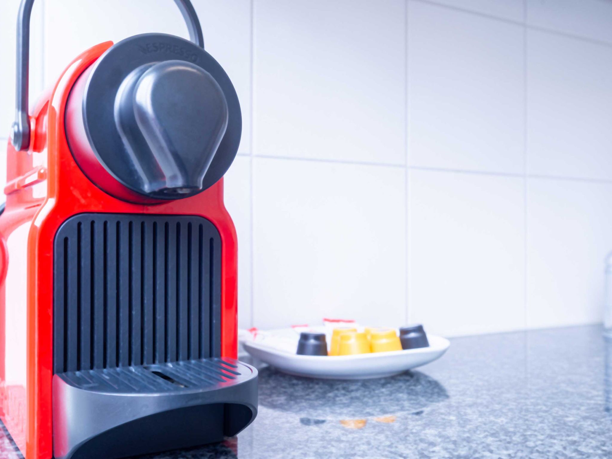 A red espresso machine with a black base on a kitchen counter.