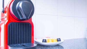 A red espresso machine with a black base on a kitchen counter.
