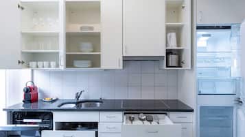 A modern kitchen with white cabinets, a black countertop, and a built-in dishwasher.