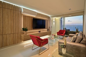 A modern living room with a flat-screen TV, red and grey sofas, a glass coffee table, and a view of the city. - Luxury apartment in cartagena| design +comfort (Cartagena de Indias)