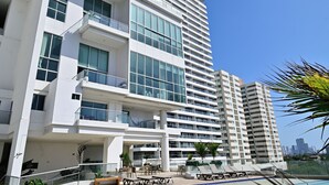 Ein modernes Hochhaus-Hotel mit Schwimmbad, mehreren Balkonen und blauem Himmel.