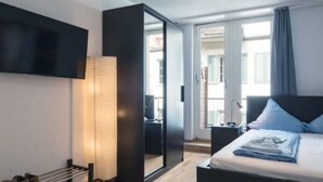 Una moderna camera d'albergo con un letto, una televisione a parete, un comodino, una lampada e vista all'esterno.