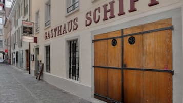 Un edificio con un letrero que dice 'GASTHAUS SCHIFF' y una puerta de madera con contraventana cerrada.