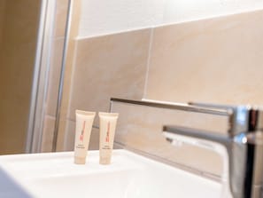 Zwei Flaschen von HIT Miet-Haar- und Körperpflegeprodukten auf einem Waschtisch.