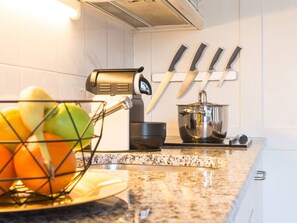 Eine Küche mit Obstkorb, Wasserkocher, Kochtopf und Messern an der Wand.