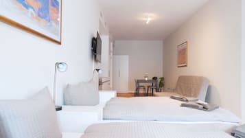 A hotel room with two beds, a desk, a chair, a TV, and a painting on the wall.