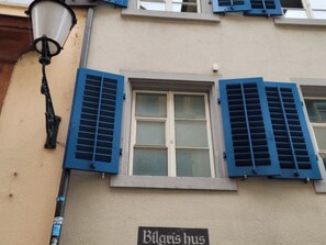 Ein Gebäude mit blauen Fensterläden, einem Schild mit der Aufschrift 'Bilgris hus' und einer Straßenlaterne.