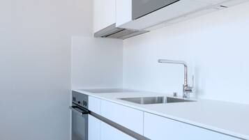 A modern kitchen with white cabinetry, a stainless steel sink, and a built-in oven.