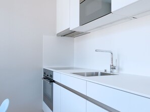 Een moderne keuken met witte kastjes, een roestvrijstalen spoelbak en een ingebouwde oven.