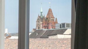 A view of a building with a distinctive red and green roof through a window. - Apartment  by Interhome (Basel)