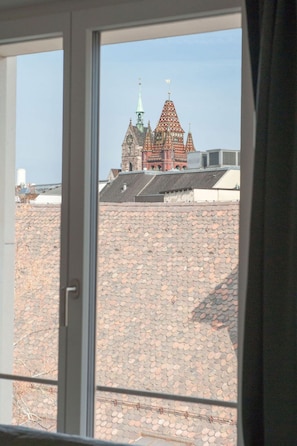 A view of a building with a distinctive red and green roof through a window. - Apartment  by Interhome (Basel)