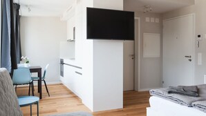 A modern hotel room with a flat-screen TV, a kitchenette, a dining area, and a separate sleeping area. - Apartment  by Interhome (Basel)