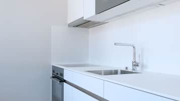 A modern kitchen with white cabinetry, a stainless steel sink, and a built-in oven.