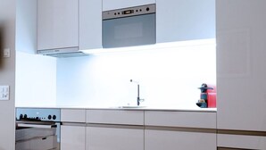 Une cuisine moderne avec des meubles blancs, un four encastré et une hotte de cuisinière en acier inoxydable.