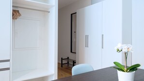 Une pièce moderne avec une table en bois foncé, des meubles blancs et une orchidée en pot.