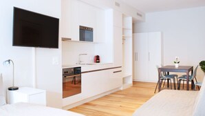 Une cuisine moderne avec des meubles blancs, un four encastré et un coin repas comprenant une table et des chaises.