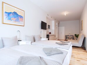 Una camera d'albergo moderna con due letti, una scrivania, una sedia e un tavolo da pranzo.