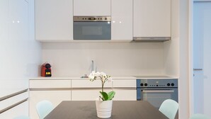 Une cuisine moderne avec des meubles blancs, un four encastré et une horloge numérique.